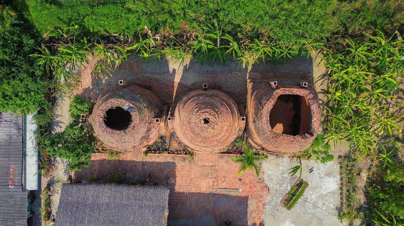 A panoramic drone view of a cluster of three Sa Đéc brick kilns, standing out in the fired-brick red amid the fresh green of Đồng Tháp's nature.