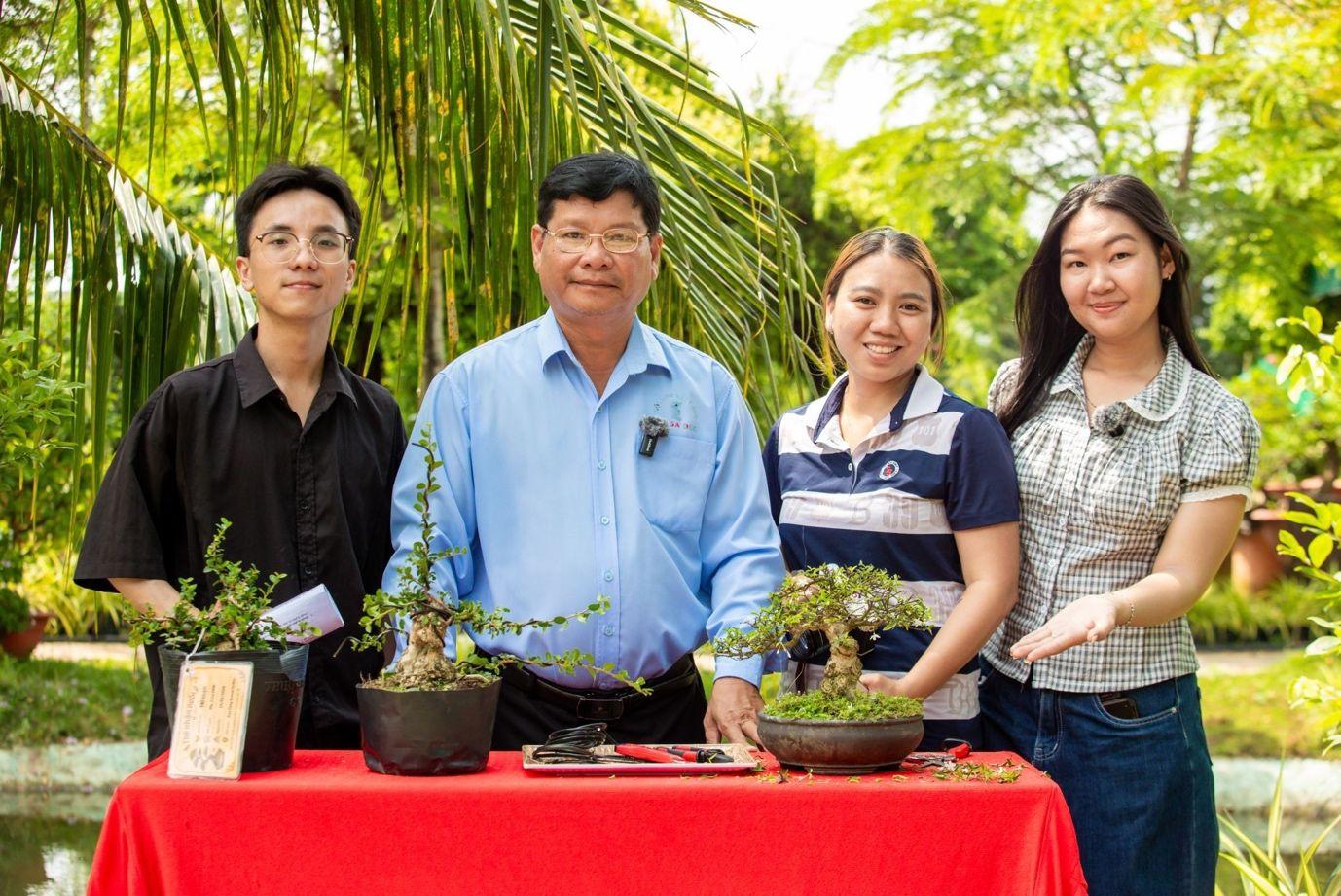Young people excitedly taking souvenir photos with an artisan and unique ornamental plants while experiencing Mekong flower-village tourism at the Sa Đéc flower village.